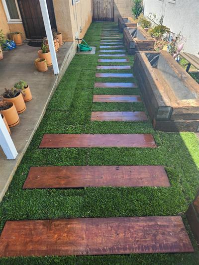Wood stepping boards installed through a narrow green sod walkway